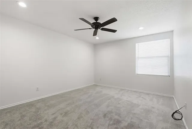 an empty room with window and ceiling fan