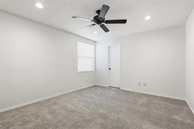 an empty room with a window and a ceiling fan
