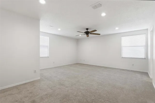 an empty room with windows and fan view