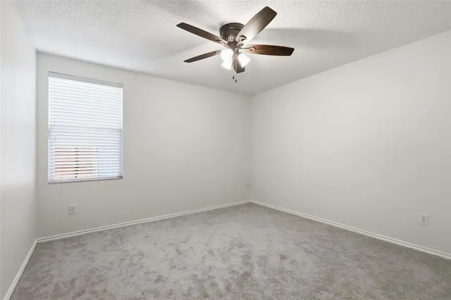 an empty room with a window and a fan