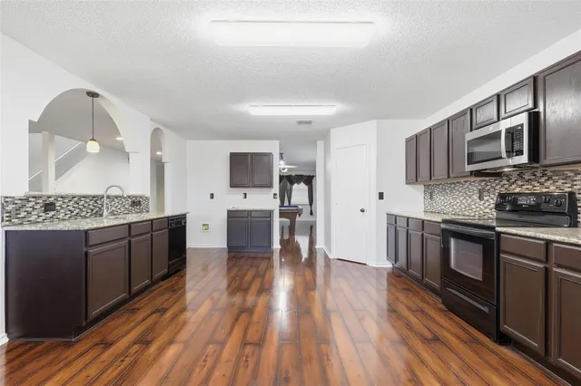 a large kitchen with a wooden floor and stainless steel appliances