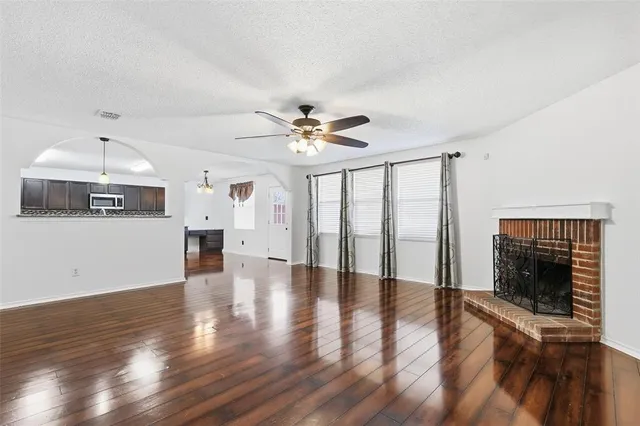 a view of an empty room with wooden floor and a fireplace