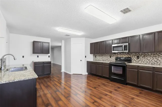 a large kitchen with granite countertop stainless steel appliances and wooden cabinets