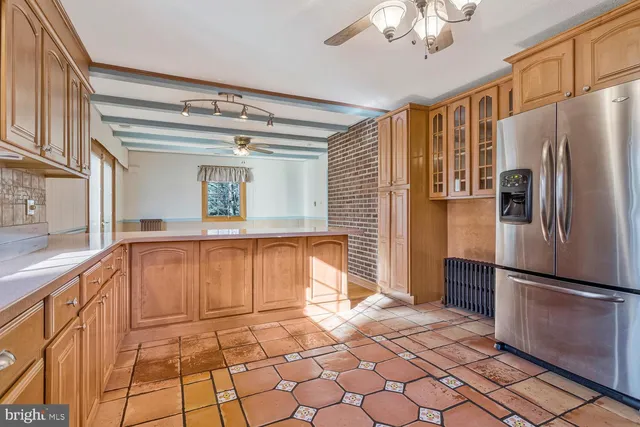 a large kitchen with a refrigerator a microwave and cabinets