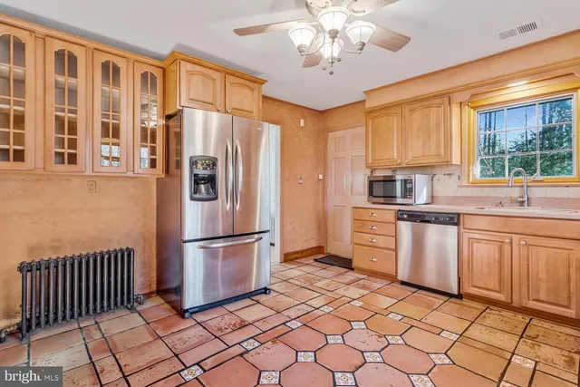 a kitchen with stainless steel appliances granite countertop a refrigerator a sink dishwasher a stove with wooden cabinets and dining table