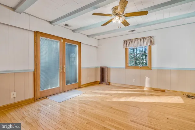 a view of an empty room with window and wooden floor