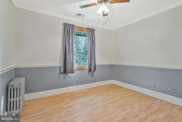 an empty room with chandelier fan and windows