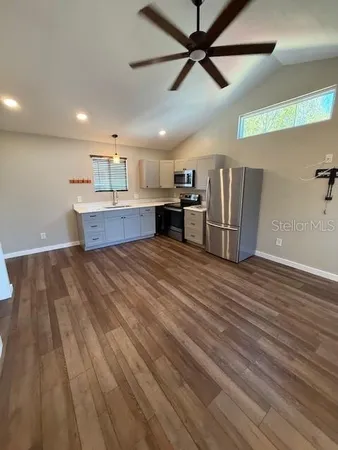 a large kitchen with stainless steel appliances a large counter top and a chandelier