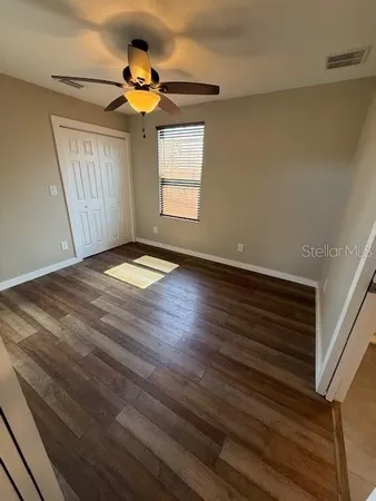 a view of empty room with wooden floor and fan