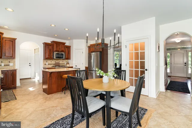 a kitchen with stainless steel appliances kitchen island granite countertop a table chairs and a refrigerator