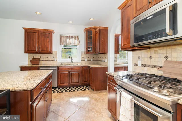 a kitchen with stainless steel appliances granite countertop a stove top oven a sink a dining table and chairs