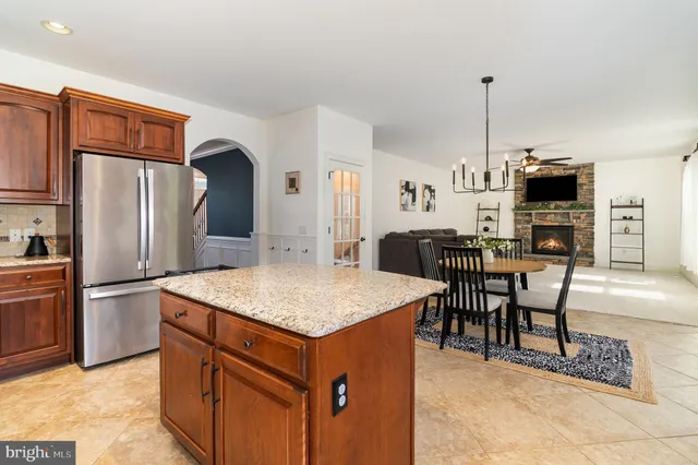 a kitchen with stainless steel appliances granite countertop a refrigerator a stove a sink a dining table and chairs with wooden floor