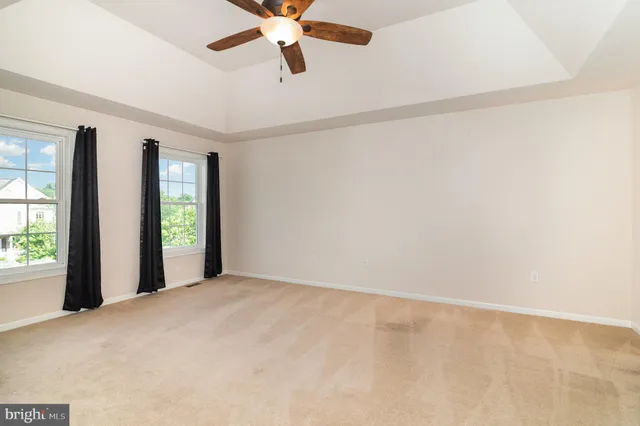 an empty room with windows and fan