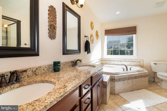 a bathroom with a granite countertop tub a sink and a window