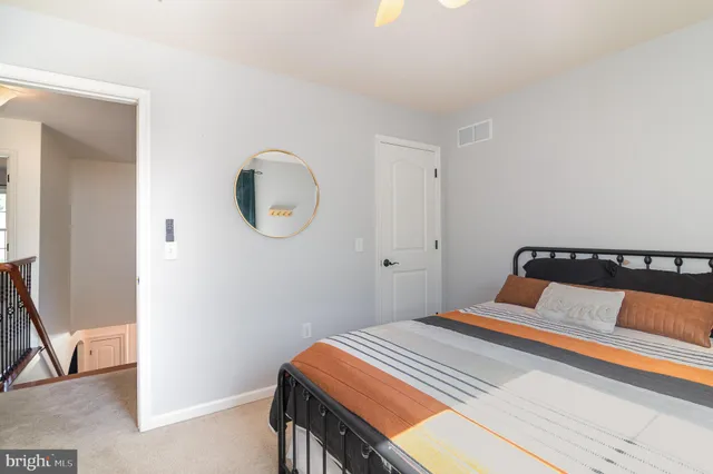 a bedroom with a bed and a potted plant on the dresser