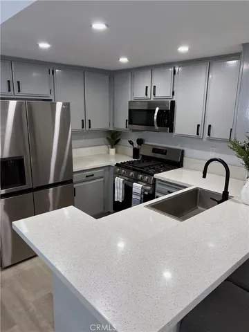 a kitchen with stainless steel appliances a refrigerator a sink a stove top oven a sink and chairs