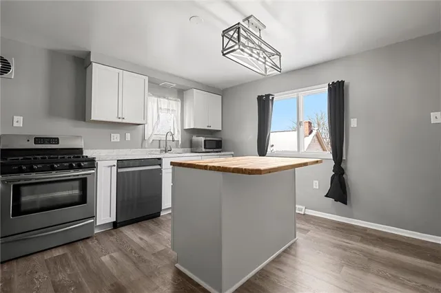 a kitchen with kitchen island granite countertop a sink cabinets and stainless steel appliances