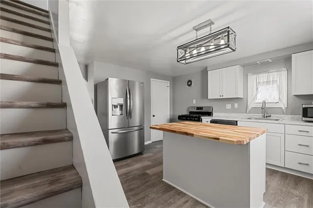 a kitchen with stainless steel appliances a refrigerator a sink and white cabinets