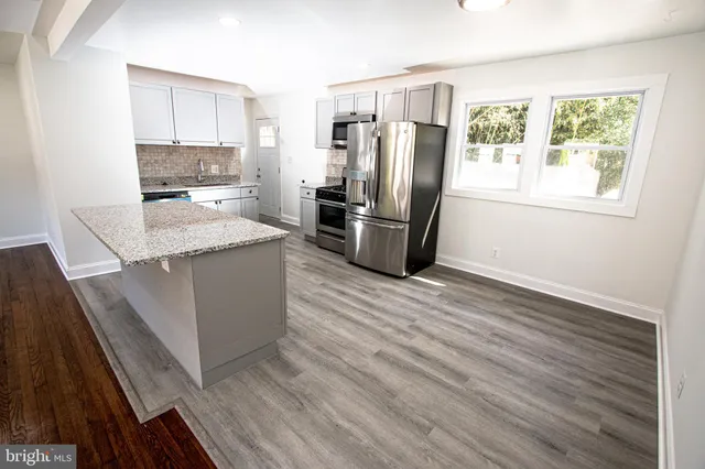 a kitchen with stainless steel appliances granite countertop a refrigerator a stove and a wooden floors