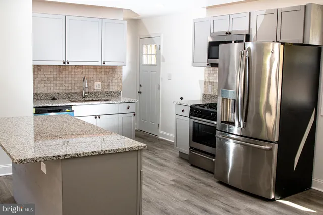 a kitchen with granite countertop a refrigerator sink and cabinets