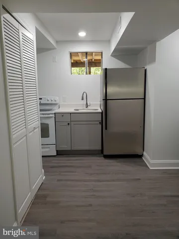 a kitchen with stainless steel appliances granite countertop a sink a stove a refrigerator and island with wooden floor