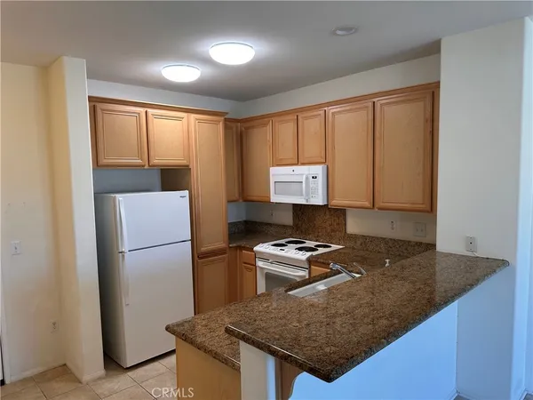 a kitchen with granite countertop a refrigerator stove and sink