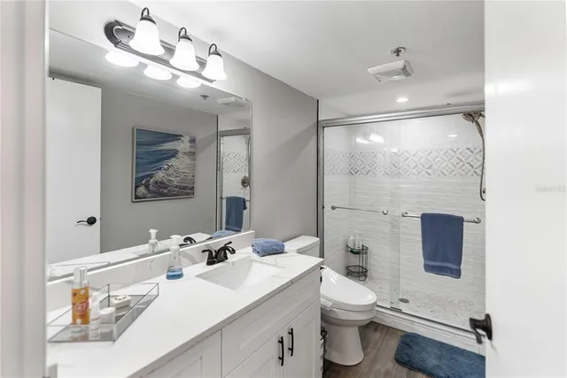 a bathroom with a sink a toilet a mirror and shower