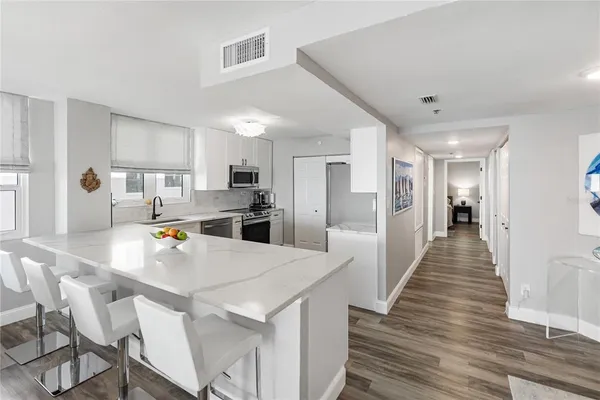 a kitchen with stainless steel appliances granite countertop a stove top oven a sink dishwasher and a refrigerator with wooden floor