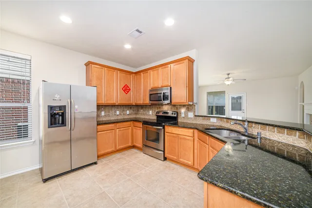 a kitchen with granite countertop a sink a counter top space stainless steel appliances cabinets and a window