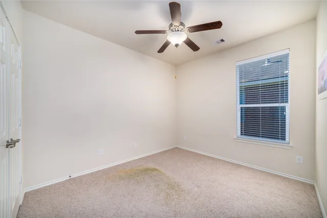 an empty room with a chandelier fan and windows