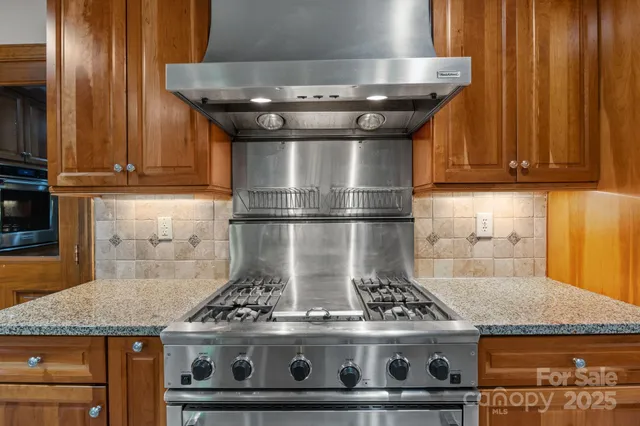 a stove sitting inside of a kitchen with granite countertop wooden cabinets