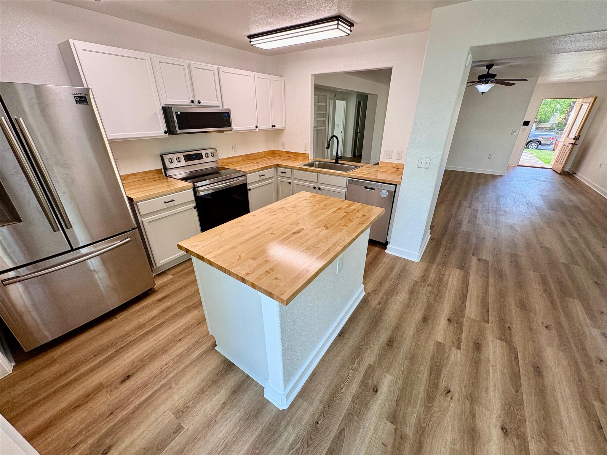 8003 Bannock Lane Austin, TX 78747 - Photo 9 of 40 Kitchen featuring stainless steel appliances, wooden counters, light wood finished floors, and a textured ceiling
