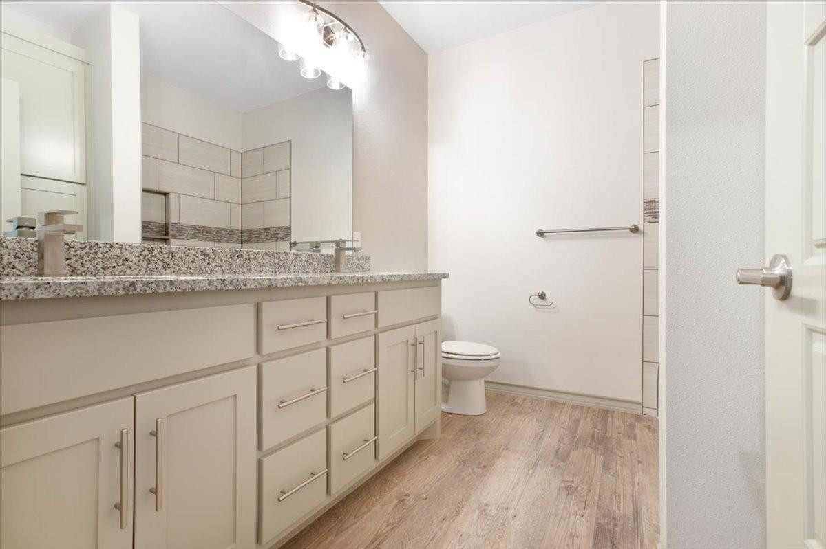 5846 Harvard Street Lubbock, TX 79416 - Photo 17 of 24 a bathroom with a granite countertop sink a toilet and a mirror