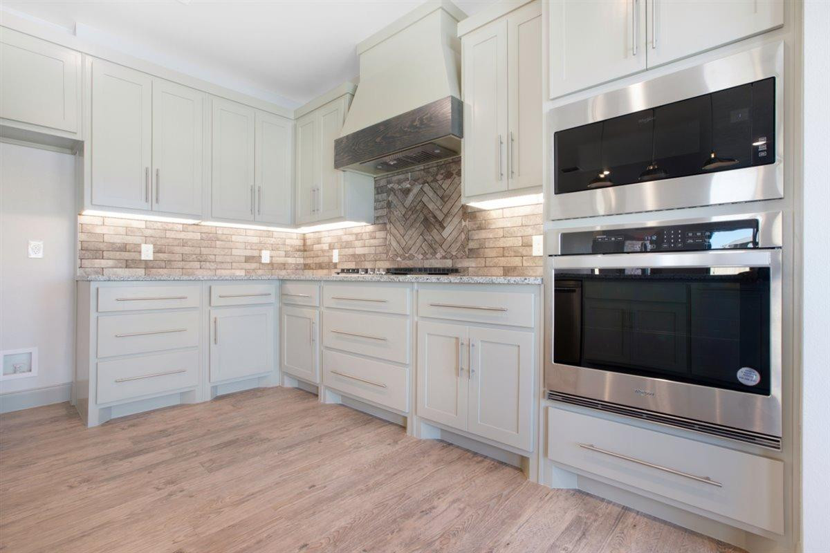 5846 Harvard Street Lubbock, TX 79416 - Photo 10 of 24 a kitchen with stainless steel appliances white cabinets and a stove top oven