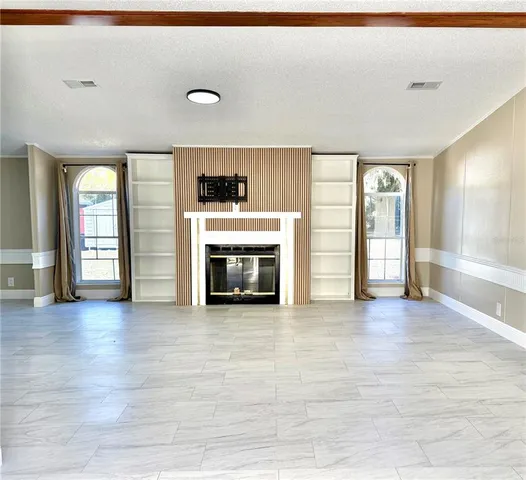 an empty room with wooden floor fireplace and windows