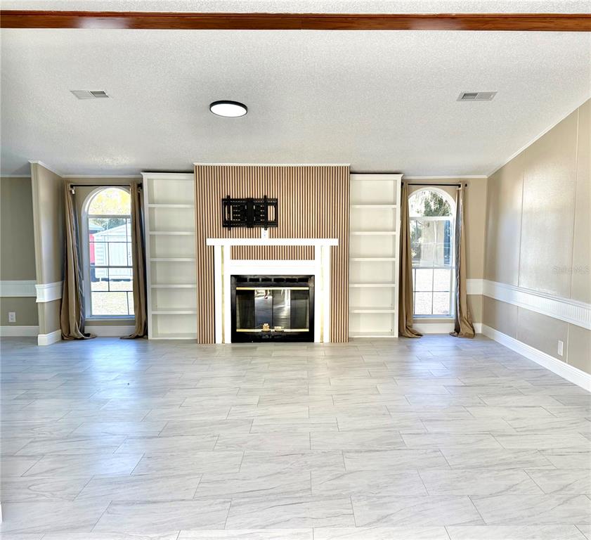 17726 Dorman Road Lithia, FL 33547 - Photo 3 of 16 an empty room with wooden floor fireplace and windows