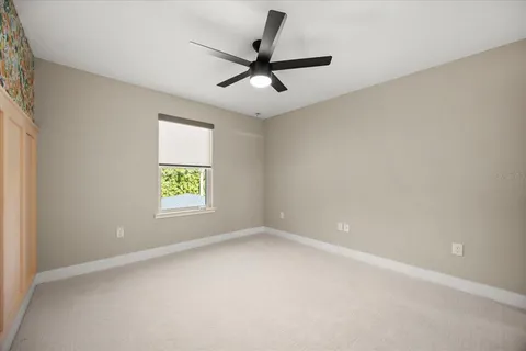 an empty room with a window and a fan