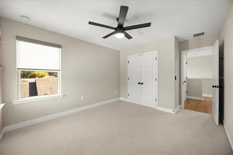a view of a livingroom with a ceiling fan & windows