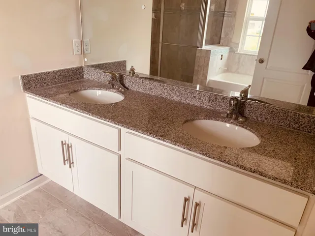 a bathroom with granite countertop double vanity and two mirror