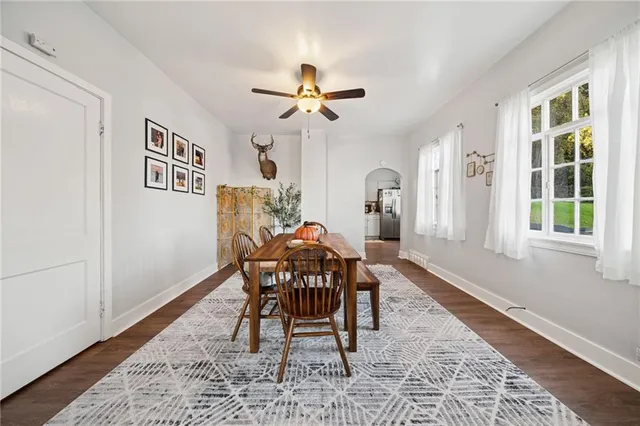 a dining room with wooden floor a chandelier fan a wooden table and chairs