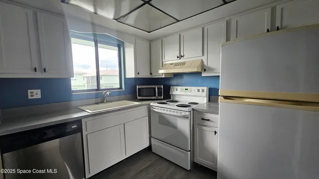 a kitchen with cabinets appliances a sink and a window