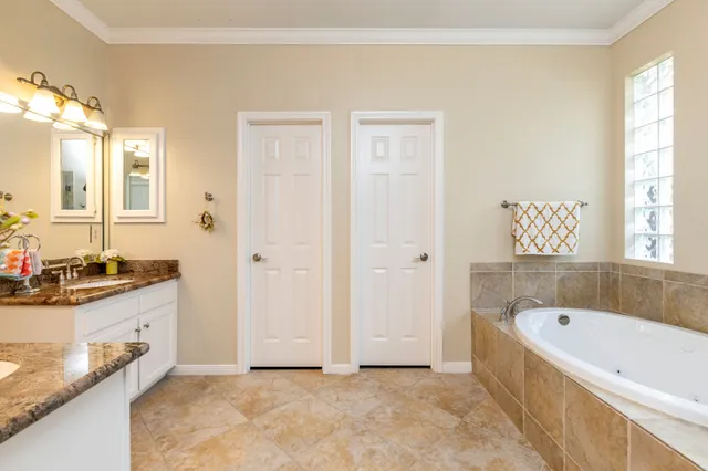 a bathroom with a granite countertop tub a sink and a window
