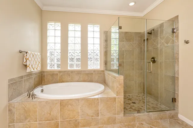 a bathroom with a tub a window and a glass door shower