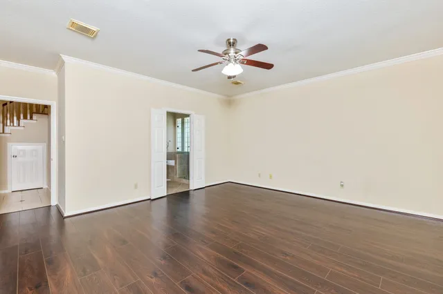 an empty room with wooden floor fan and windows