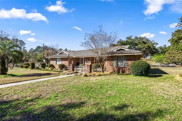 a white house with a big yard and large trees