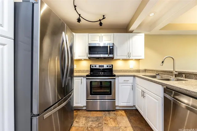 a kitchen with stainless steel appliances granite countertop a refrigerator a stove and a sink