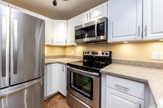 a kitchen with stainless steel appliances granite countertop white cabinets a stove a microwave and a refrigerator