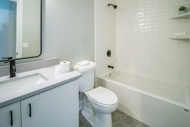 a bathroom with a granite countertop sink toilet a large mirror a shower and a bathtub