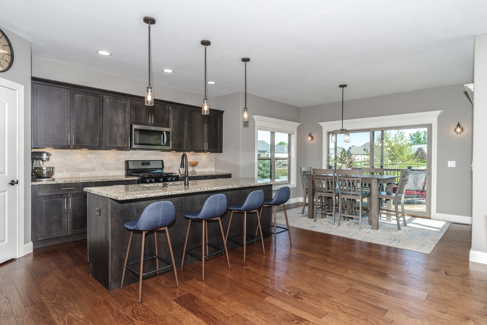 15924 Belfry Drive Bloomington, IL 61705 - Photo 22 of 59 a kitchen with stainless steel appliances granite countertop a stove top oven a sink a dining table and chairs with wooden floor