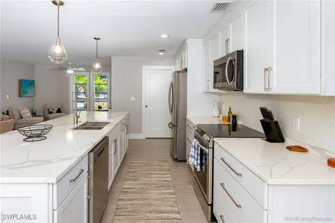 a kitchen that has a lot of white cabinets and stainless steel appliances
